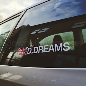 May include: A silver car with a sticker on the rear window. The sticker features a Union Jack flag and the text "D.DREAMS".