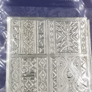 May include: A sheet of self-adhesive metallic embellishments with a geometric pattern. The embellishments are silver and have a textured surface. The packaging says "Self-Adhesive Metallic Embellishments Magenta Style".