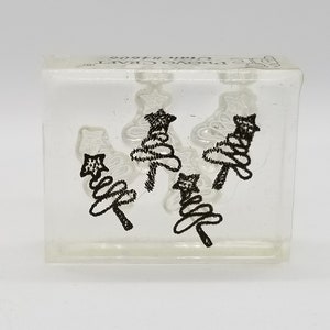 May include: A clear acrylic block with four black and white Christmas tree stamps. The stamps are in the shape of a stylized Christmas tree with a star on top.