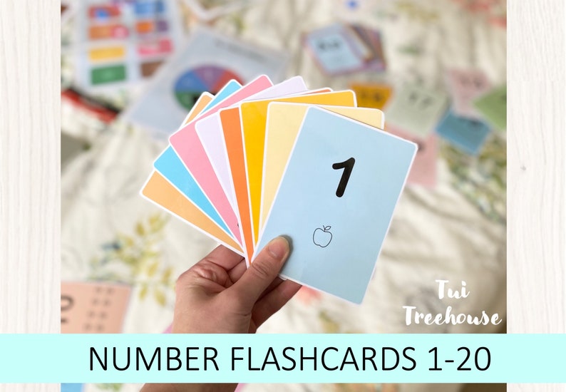 Puede incluir: Un conjunto de tarjetas de n&uacute;meros de colores con una tarjeta azul claro que muestra el n&uacute;mero "1" y una peque&ntilde;a ilustraci&oacute;n de una manzana. El texto "NUMBER FLASHCARDS 1-20" est&aacute; en la parte inferior de la imagen. El texto "Tui Treehouse" est&aacute; en la esquina inferior derecha de la imagen.