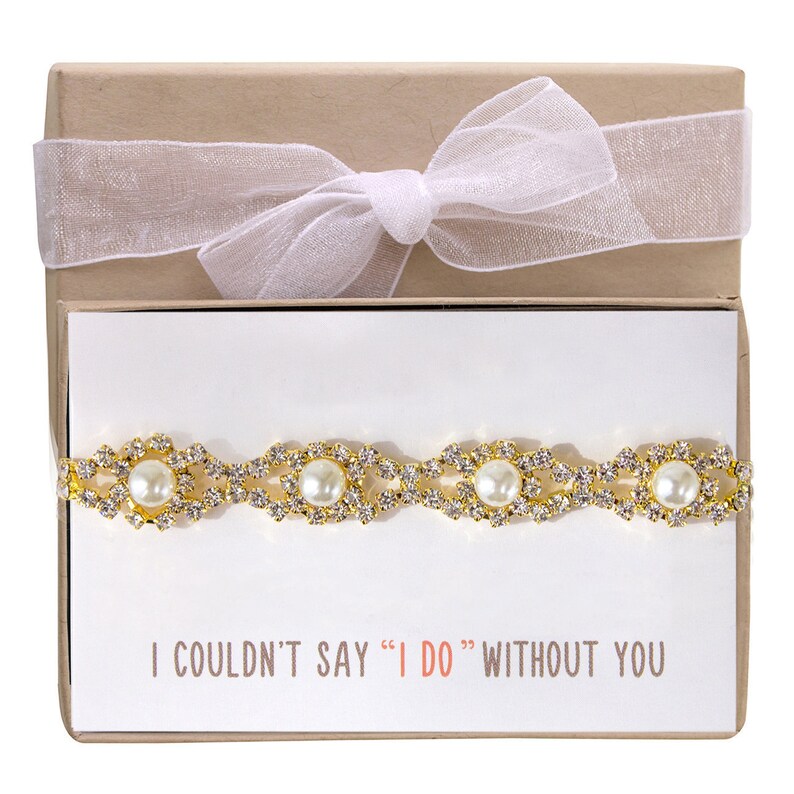 May include: A gold and white bracelet with pearls and rhinestones in a gift box with a white ribbon. The card inside the box reads 'I couldn't say 'I do' without you.'
