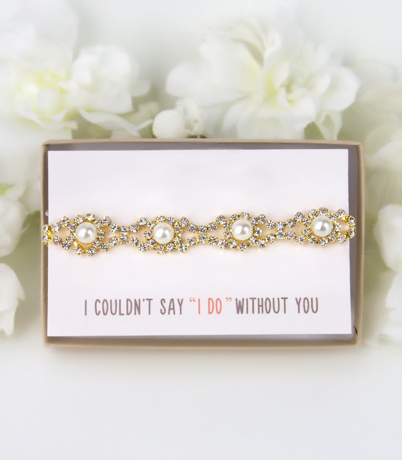May include: A small white box containing a gold and pearl bracelet. The box has a white card with the text "I couldn't say "I do" without you".