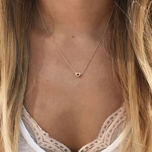 May include: A delicate gold necklace with a small, twisted circle pendant.