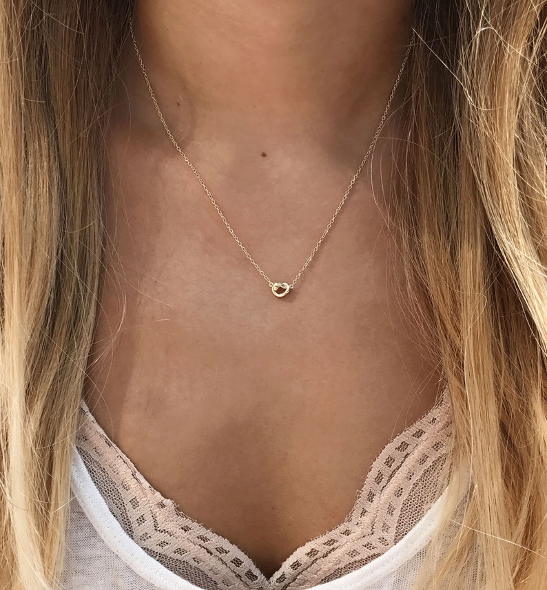 May include: A delicate gold necklace with a small, twisted circle pendant.