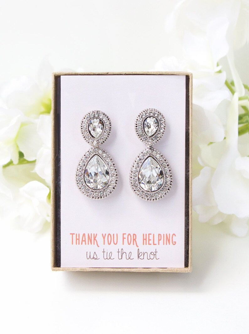 May include: A pair of silver teardrop earrings with clear crystal stones. The earrings are in a small box with a white card that says 'Thank you for helping us tie the knot'.