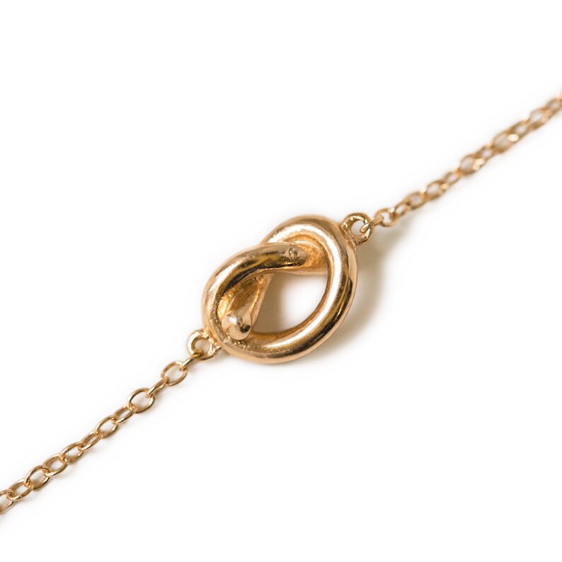 May include: A gold chain necklace with a knot-shaped pendant.