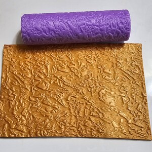 May include: A purple textured roller for creating a crinkled effect on fondant or other cake decorating materials. The roller is shown next to a sample of the texture it creates.