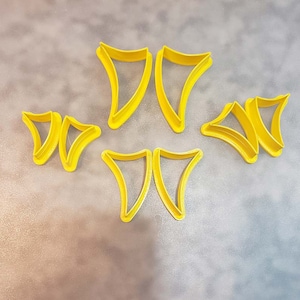 May include: Set of six yellow plastic cookie cutters shaped like a pointed triangle. The cutters are arranged in two rows of three.