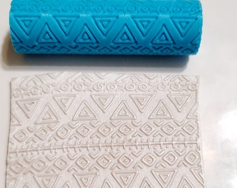 May include: A blue rolling pin with a geometric pattern embossed on the surface. The rolling pin is used to create a textured pattern on fondant or clay.