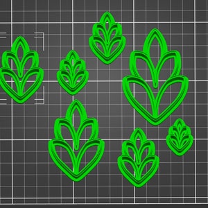 May include: A collection of seven green, leaf-shaped cookie cutters in various sizes. The cutters are arranged on a dark gray grid background, showcasing their detailed floral design. The shapes are ideal for creating decorative cookies or fondant decorations.