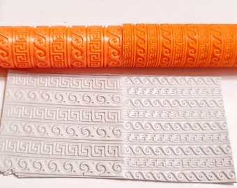 May include: Orange rolling pin with a repeating pattern of Greek key and wave designs. The rolling pin is used to create an embossed pattern on a white surface.