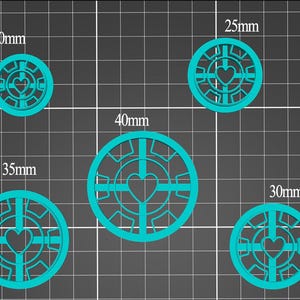 Könnte beinhalten: Fünf türkisfarbene, kreisförmige Objekte mit herzförmigem Ausschnitt. Die Durchmesser betragen 20mm, 25mm, 30mm, 35mm und 40mm. Jedes Objekt hat ein geometrisches Muster um das Herz herum, auf einem Rasterhintergrund.