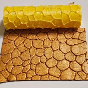May include: A yellow plastic rolling pin with a honeycomb pattern, and a brown textured sheet with a stone pattern.