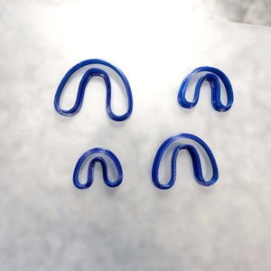 May include: Four blue plastic cookie cutters shaped like a horseshoe.
