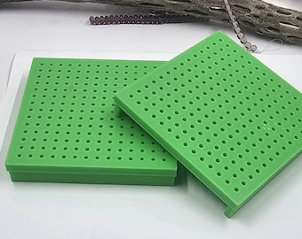 May include: Two green plastic pegboards with a grid of holes. The pegboards are stacked on top of each other.
