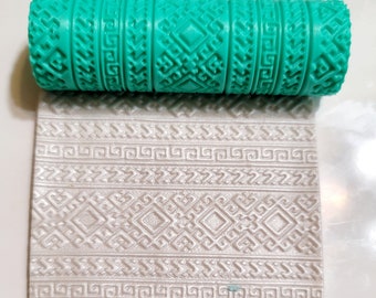 May include: A teal rolling pin with a geometric pattern design. The rolling pin is used to create an embossed pattern on fondant or dough.