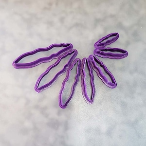 May include: A set of seven purple plastic cookie cutters shaped like leaves.