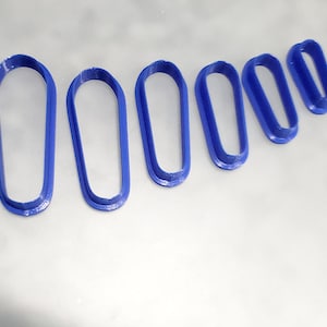 Könnte beinhalten: Satz mit sechs blauen Plastik-Ausstechern in Ovalform, angeordnet in absteigender Grössenordnung.