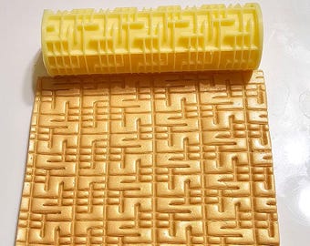 Può includere: Un mattarello di plastica giallo con un motivo geometrico. Il mattarello viene utilizzato per creare un design testurizzato su fondant o altri materiali commestibili.