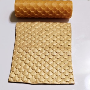 May include: A gold-colored rolling pin with a scale pattern, used for creating decorative patterns in fondant or clay.