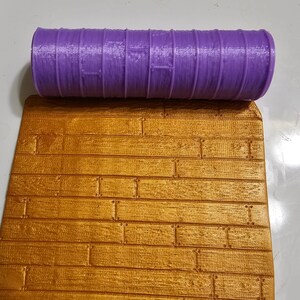 May include: A purple rolling pin with a wood grain pattern. The rolling pin is used to create a wood plank texture on fondant or clay.