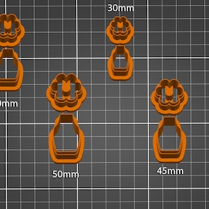 Puede incluir: Cuatro cortadores de galletas en naranja y verde, con forma de flor y jarrón. Los cortadores tienen un tamaño de 30 mm, 35 mm, 40 mm, 45 mm y 50 mm.