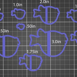 May include: A collection of blue, fish-shaped cookie cutters of varying sizes, ranging from 0.50 inches to 3.0 inches in length. The cutters are displayed on a dark gray grid background, with measurements in inches clearly labeled next to each cutter.