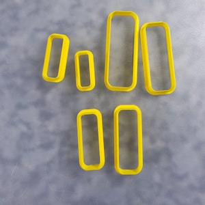 May include: Set of seven yellow plastic rectangle cookie cutters of varying sizes.