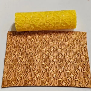 May include: A yellow rubber roller with a wavy pattern, used for creating a textured effect on leather. The roller is shown next to a piece of brown leather with the same wavy pattern embossed on it.