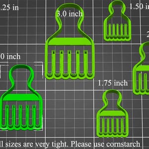 May include: Five green plastic cookie cutters shaped like an afro pick. The cutters are different sizes, ranging from 1.25 inches to 3 inches. The text "Small sizes are very tight. Please use cornstarch" is at the bottom of the image.