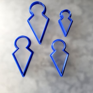 May include: Four blue plastic cookie cutters shaped like a pointed teardrop with a circle at the top. The cutters are different sizes.