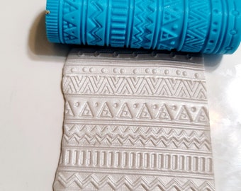 May include: A blue rolling pin with a geometric pattern design. The rolling pin is used to create decorative patterns in fondant or clay.