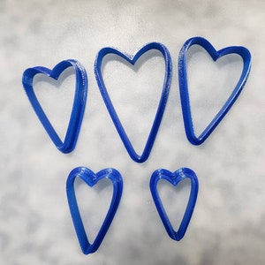 May include: Five blue heart-shaped cookie cutters of different sizes.