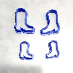 May include: Four blue plastic cookie cutters shaped like cowboy boots. The cutters are in two sizes, with two of each size.