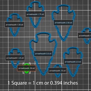 May include: A set of nine blue arrowhead-shaped cookie cutters of varying sizes, ranging from 0.50 inches to 3.0 inches in diameter. The cookie cutters are arranged on a gray grid background with a scale of 1 cm or 0.394 inches per square.