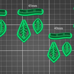 May include: Set of six green plastic cookie cutters in various sizes. The cutters are shaped like leaves with a detailed vein pattern. The cutters are labeled with measurements in millimeters: 50mm, 45mm, 40mm, and 35mm.