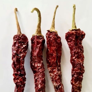 May include: Four dried red chili peppers with stems. The peppers are wrinkled and have a dark red color.
