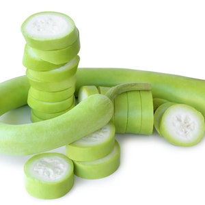 Puede incluir: Un conjunto de calabazas botella verdes frescas, algunas enteras y otras cortadas en rodajas. Las rodajas revelan un interior blanco. Las calabazas están dispuestas sobre un fondo blanco, resaltando su color y textura naturales.
