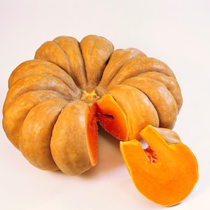 Puede incluir: Una calabaza grande, redonda y naranja con una piel lisa y ligeramente texturizada. La calabaza está cortada por la mitad, revelando la pulpa de color naranja brillante en el interior.