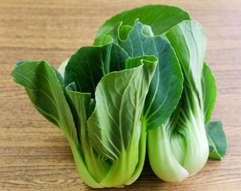 Może przedstawiać: Dwie wiązki świeżego zielonego bok choy, rodzaju chińskiej kapusty, z dużymi, zielonymi liśćmi.