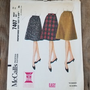 May include: Vintage McCall's sewing pattern for a skirt, pattern number 7407. The pattern is for a proportioned skirt that is easy to sew. The pattern is recommended for beginners. The pattern includes three different skirt styles: a black and white patterned skirt, a red and black plaid skirt, and a brown corduroy skirt.