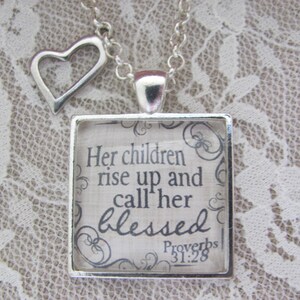 May include: A silver necklace with a heart charm and a square pendant with a quote from Proverbs 31:28. The quote reads "Her children rise up and call her blessed".