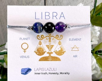 Pode incluir: Um bracelete de corda cinzento com três contas: uma conta de lapis-lazúli azul, uma conta preta e uma conta de ametista roxa. O bracelete é apresentado em um cartão com o signo do zodíaco Libra, o planeta Vénus, o elemento Ar e as palavras "Lapis Lazuli Verdade interior, Honestidade, Moralidade".