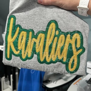 May include: A gray t-shirt with a green and yellow appliqué that says "cavaliers".