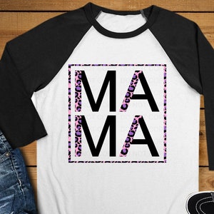 Könnte beinhalten: Ein weißes und schwarzes Baseball-T-Shirt mit einem pinkfarbenen und violetten Leopardenmuster. Das Shirt hat das Wort "MAMA" in schwarzen Buchstaben in einem quadratischen Rahmen gedruckt.