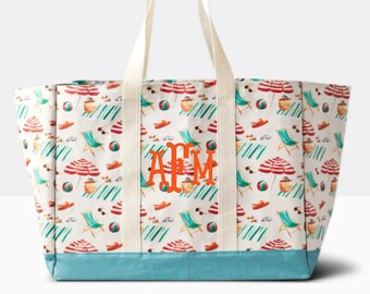 May include: A white canvas tote bag with a beach scene print featuring beach chairs, umbrellas, sunglasses, and beach balls. The bag has a blue bottom and two white straps. The bag is monogrammed with the letters "AFM" in orange.