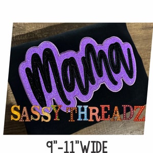 May include: Purple glitter iron-on patch with the word "Mama" in black lettering. The patch is on a black t-shirt with the text "SASSY THREADZ" in colorful letters. The t-shirt is on a wooden surface. The text "9" - 11" WIDE" is below the image.