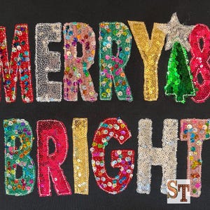 May include: A black sweatshirt with the words "Merry & Bright" in colorful sequins.