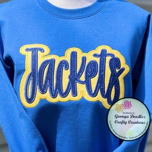 May include: A royal blue sweatshirt with a yellow and blue glitter applique that says "Jackets".