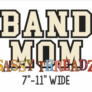 May include: A white background features the words "BAND MOM" in a bold, collegiate-style font with a black outline. Below, the text "SASSY THREADZ" is in a colorful, decorative font. The text "7"-11" WIDE" is at the bottom.